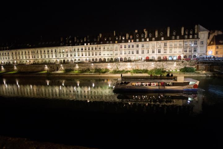 a lit up city at night in front of a body of water